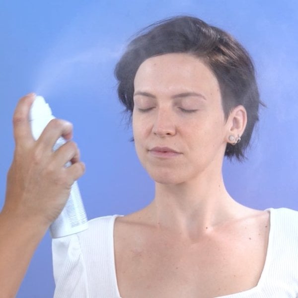 Frau sprüht sich Thermalwasserspray ins Gesicht