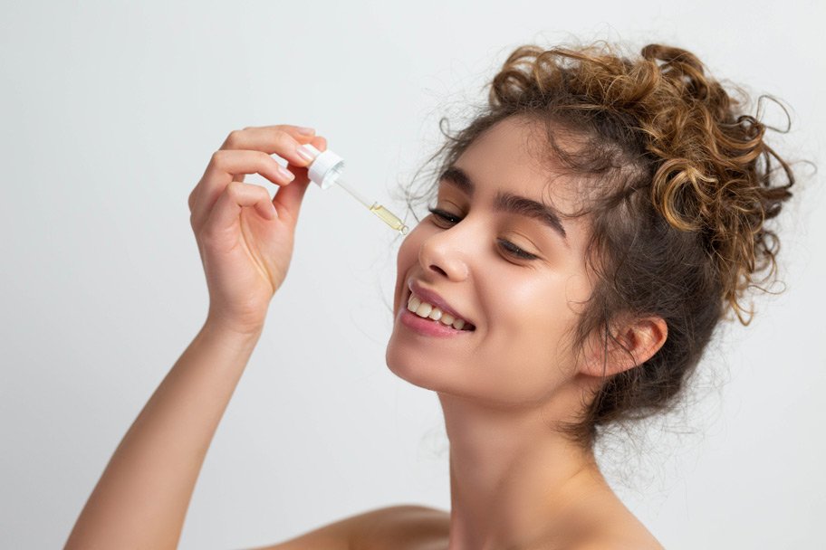 Junge Frau trägt ein Vitamin A Serum auf ihr Gesicht