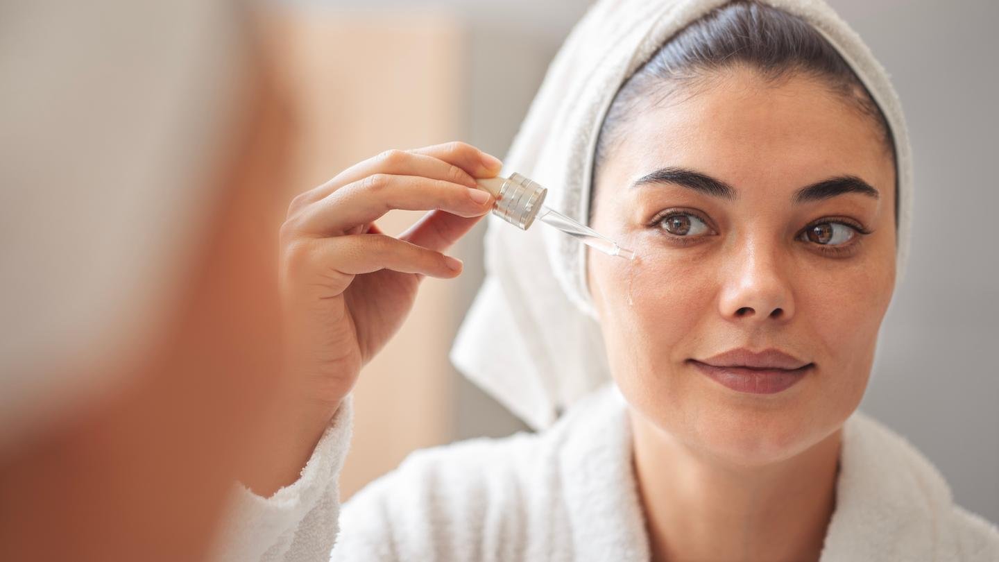 Frau trägt Hyaluron-Serum mit einer Pipette auf die Haut unter dem Auge auf.
