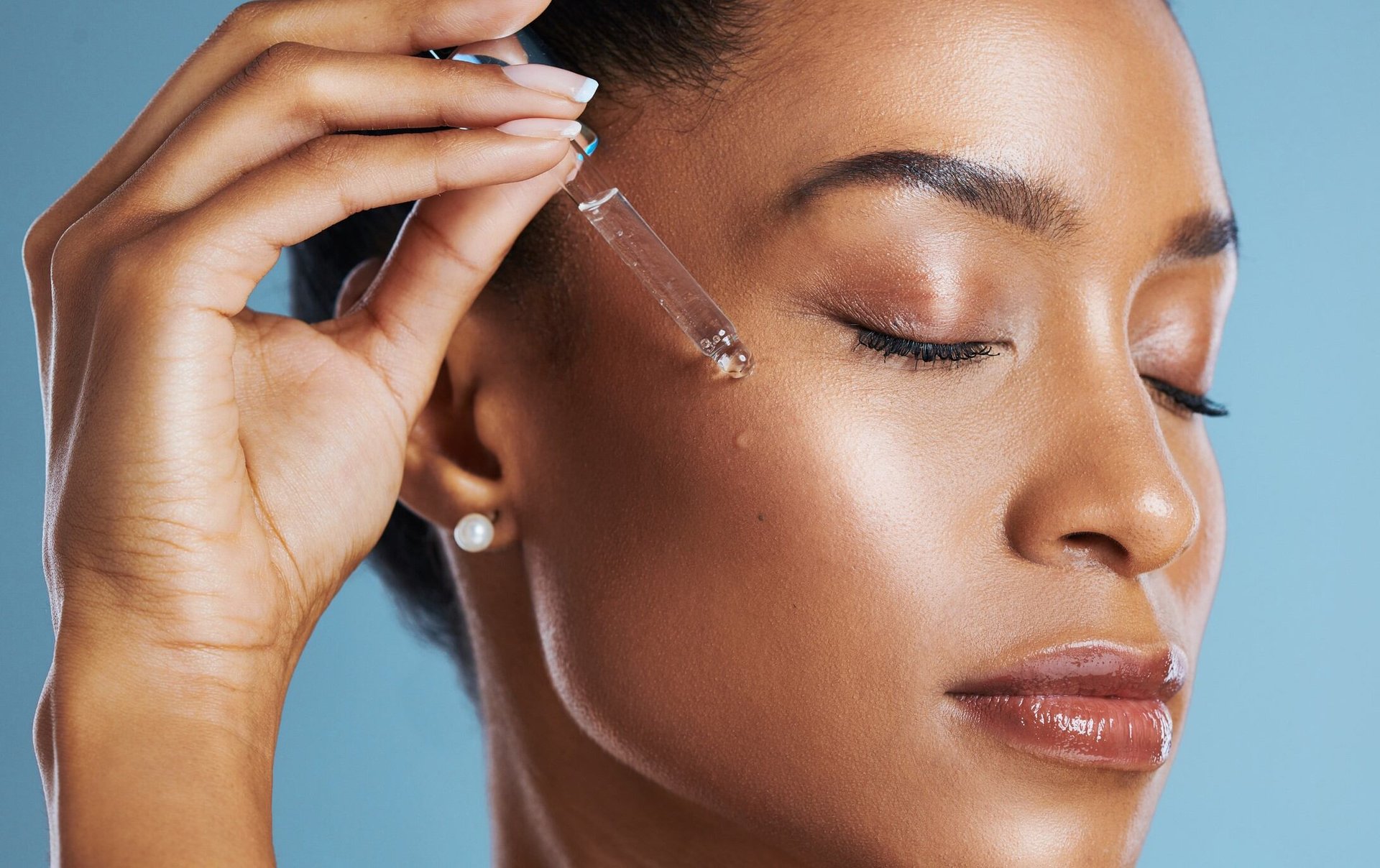Junge Frau tröpfelt Retinol-Serum auf die Wange