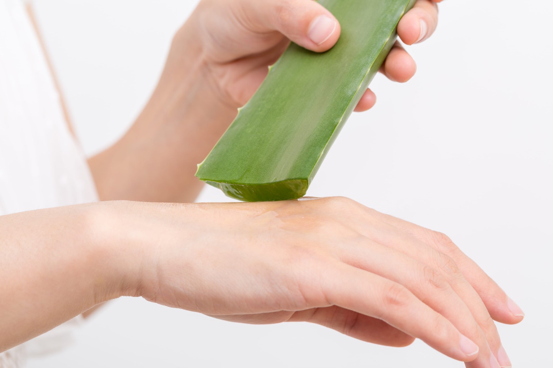 Person trägt frisches Aloe-Vera-Gel auf die Hand auf, zur Linderung trockener, zu Neurodermitis neigender Haut.