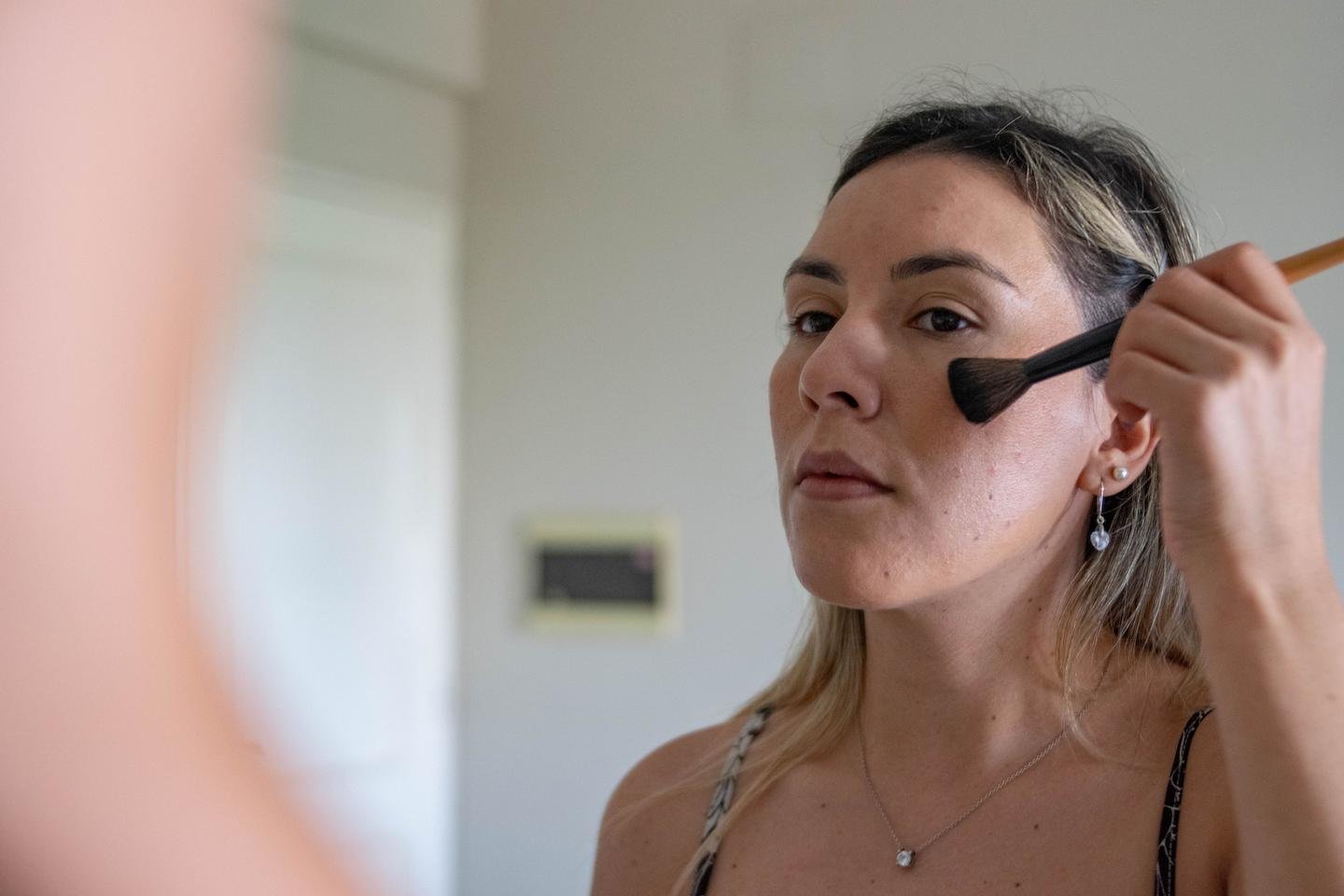 Frau trägt mit einem Pinsel Make-up auf die Wange auf