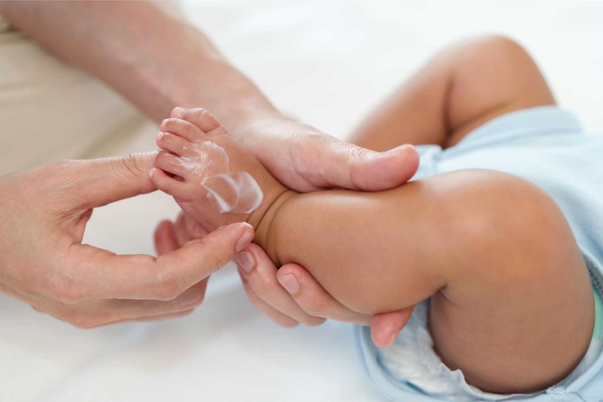 Trockene Haut bei Babys: Frau cremt den Fuß eines Babys ein