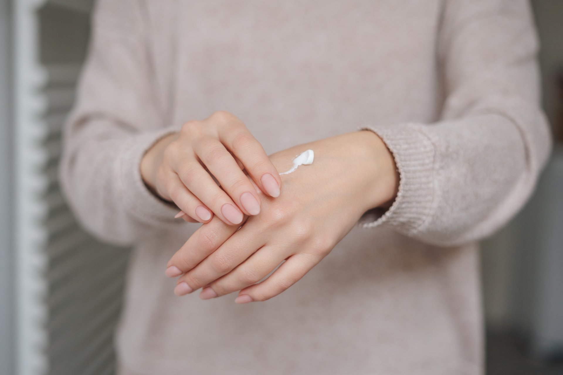 Frau trägt Handcreme auf ihre Hände 