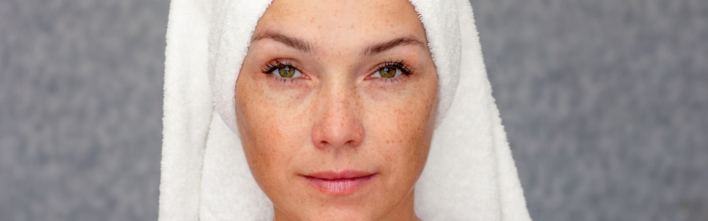 Anti-Aging: Frau mit einem Handtuch um den Kopf schaut in die Kamera