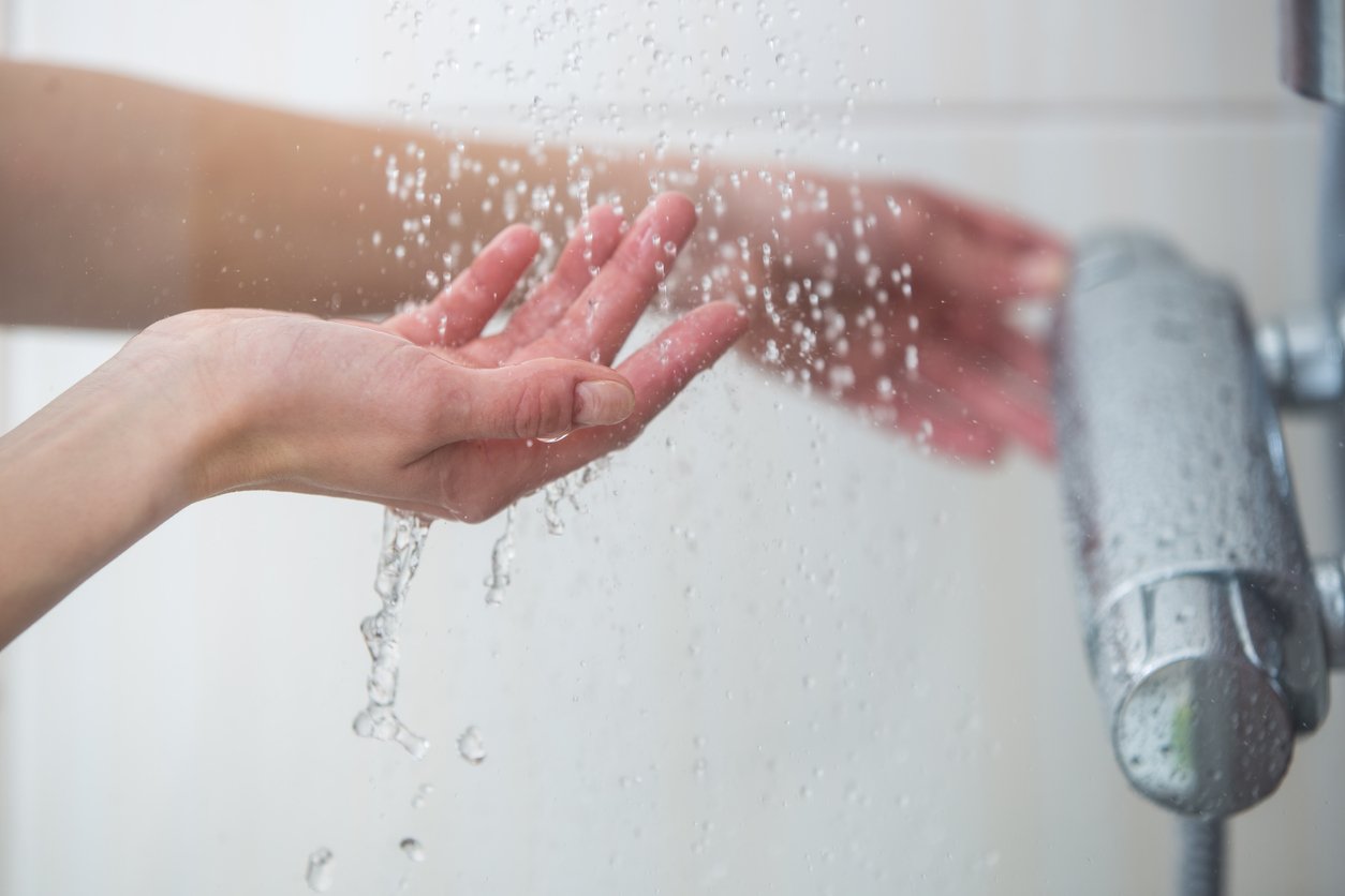 Hand unter laufendem Wasser unter der Dusche