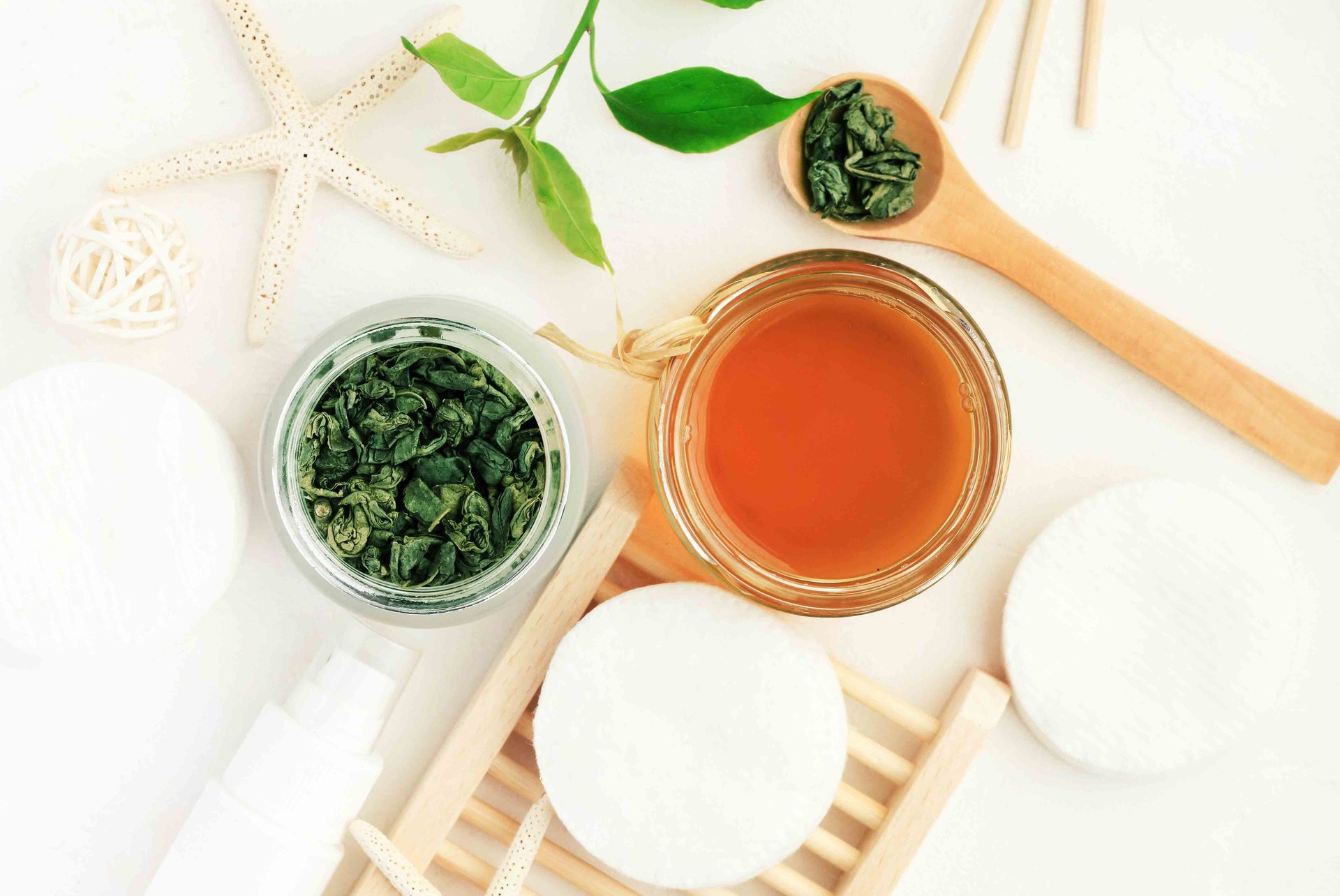 Vermeintliche Hausmittel gegen Akne und Spa-Accessoires mit grünem Tee, Glas mit Öl, Wattepads und Holzlöffel