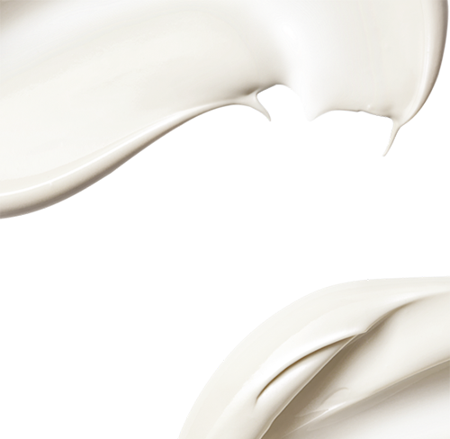 Nahaufnahme von weißer Creme, die geschmeidig und in geschwungenen Linien auf weißem Hintergrund verteilt ist.
