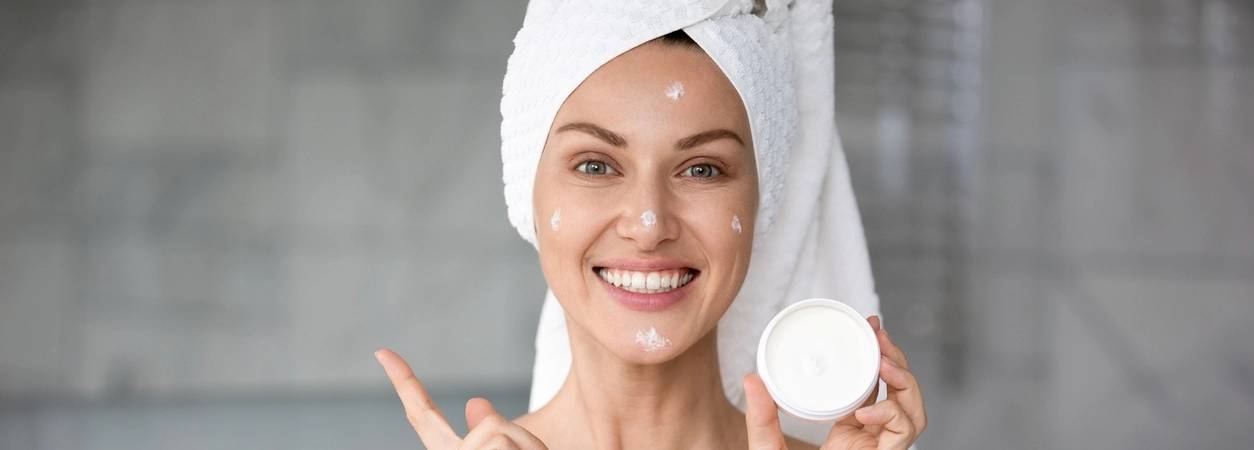Junge Frau trägt eine Creme mit Hyaluron auf ihr Gesicht auf