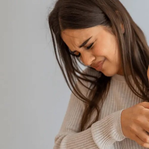 Frau mit Neurodermitis kratzt sich am Arm